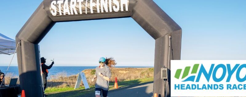 Runner crossing the finish line on the coastal trail in Fort Bragg at the 2023 Noyo Headlands Race.